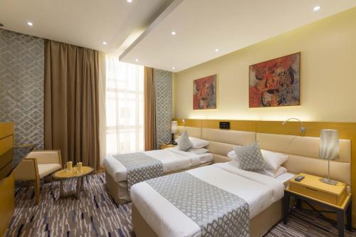 une chambre d'hôtel avec deux lits et un canapé dans l'établissement Qasr Al Sahab Hotel Makkah, à La Mecque