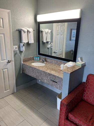baño con lavabo, espejo y silla roja en Brandon Motor Lodge en Brandon