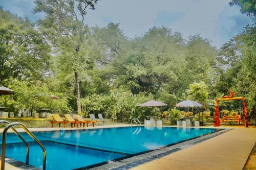 una piscina en un complejo con árboles en el fondo en Dudley Nature Resort en Habarana