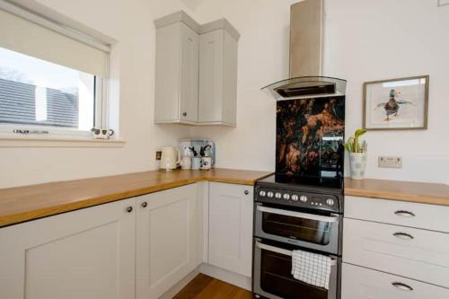 a kitchen with white cabinets and a stove top oven at South Barlogan Farm in Bridge of Weir