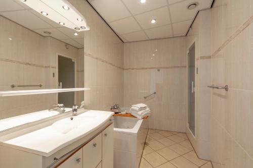 een witte badkamer met een wastafel en een douche bij De Vlijt Business class suite in De Cocksdorp