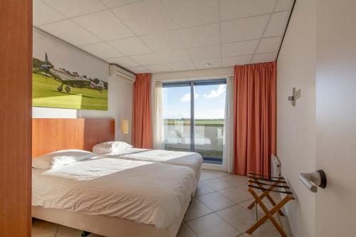 een slaapkamer met 2 bedden en een groot raam bij De Vlijt Business class suite in De Cocksdorp