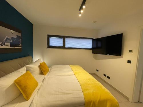 a bedroom with a bed with yellow pillows and a flat screen tv at Suite-Meerblick-Juliusruh in Juliusruh