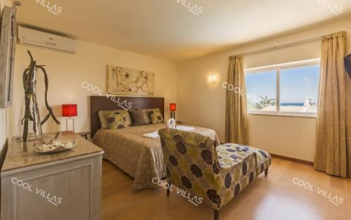 1 dormitorio con 1 cama, 1 silla y 1 ventana en Villa Gardenia - sea view, wifi, games room, en Albufeira