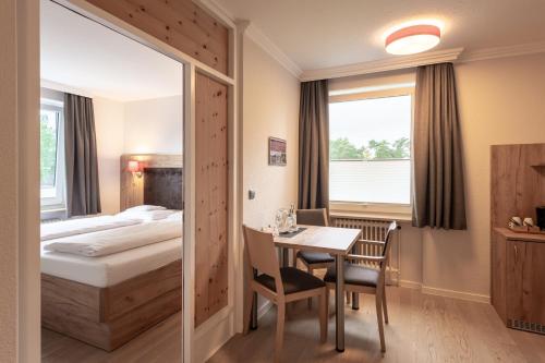 a bedroom with a bed and a table and a desk at Hotel Sonnenhügel in Bad Bevensen