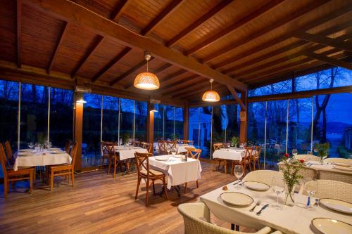 a restaurant with white tables and chairs and windows at Beta Home Sapanca in Sapanca