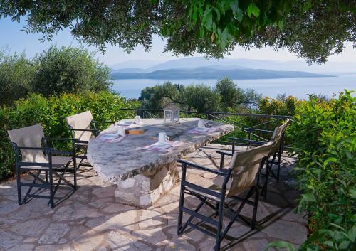 une table et des chaises en pierre avec vue sur l'eau dans l'établissement Villa Vasso Sea View Residences, à Agnítsini
