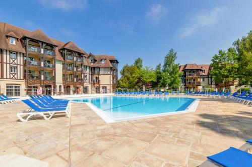 uma piscina com espreguiçadeiras azuis num resort em La Résidence du Golf de Deauville em Deauville