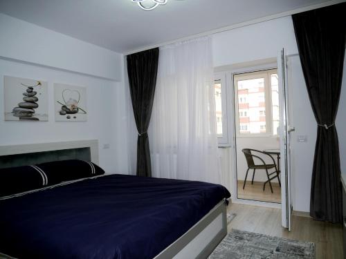 a bedroom with a bed and a balcony with a table at Apartament David in Câmpulung Moldovenesc