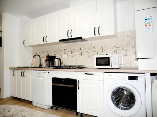 a kitchen with white cabinets and a washer and dryer at Apartament David in Câmpulung Moldovenesc