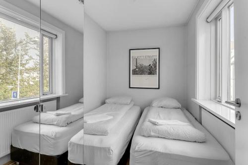 twee bedden in een kamer met twee ramen bij Central Reykjavík Apartment in Reykjavík