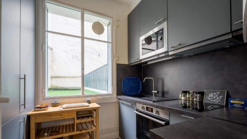 une cuisine avec un évier et une fenêtre dans l'établissement Neuilly-Sur-Seine f2 en rez de chaussée, à Neuilly-sur-Seine