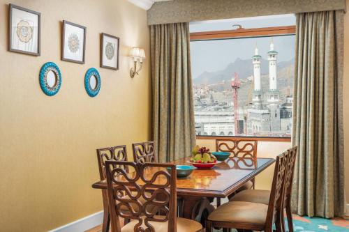 a dining room with a table and chairs and a window at Anjum Makkah Hotel in Makkah