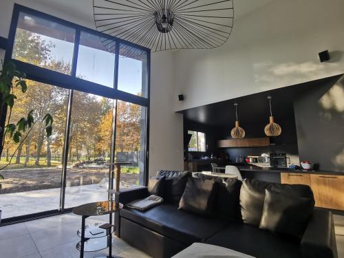 - un salon avec un canapé noir et une grande fenêtre dans l'établissement Maison moderne a 1km du circuit des 24h du mans, à Arnage