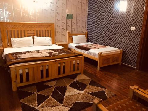 1 dormitorio con 2 camas y alfombra en Alaf Laila Guest House, en Abbottābād