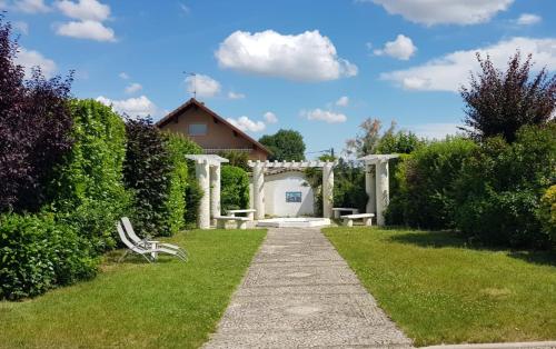 a garden with an arch and a bench in the grass at La Casa Blanca in Janneyrias