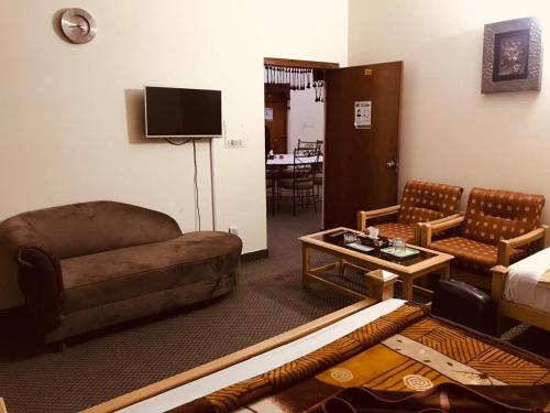 a living room with a couch and a bed and a table at Alaf Laila Guest House in Abbottābād