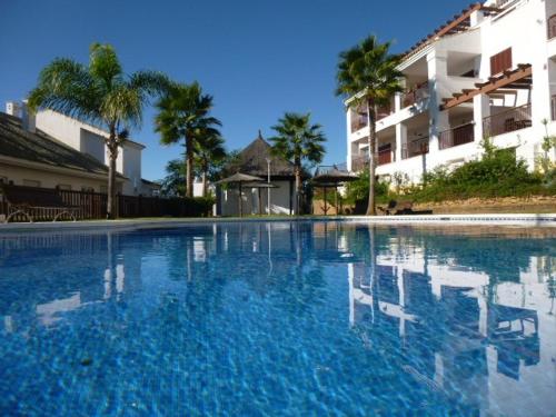 a large swimming pool with two chairs in front of a building at Nueva Alcaidesa 2104 - Sea Sun and Green in San Roque