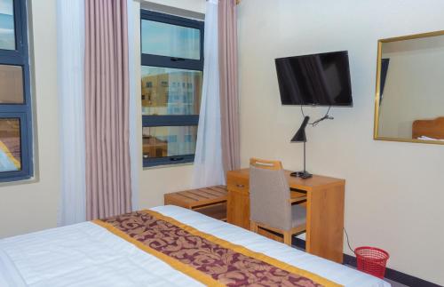a hotel room with a bed and a desk and a television at Tropical Plaza Apartments in Kigali
