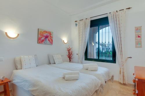 - une chambre blanche avec 2 lits et une fenêtre dans l'établissement La Almadraba 312, à Manilva
