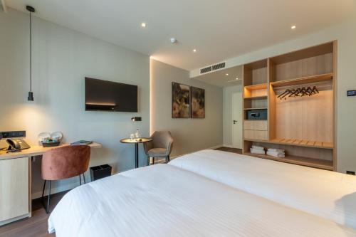 a hotel room with a large white bed and a desk at The CORNR Hotel in Nieuwpoort