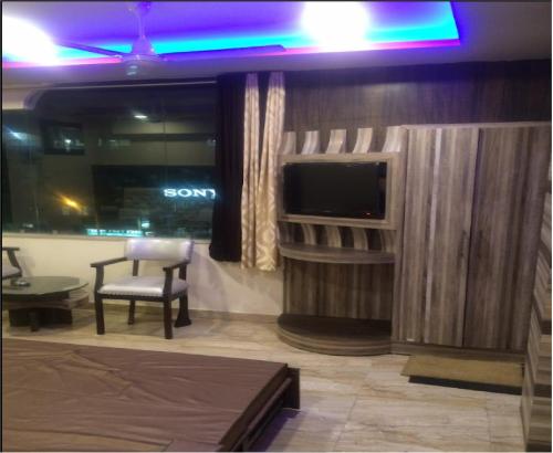 Cette chambre dispose d'une télévision, d'une chaise et d'une table. dans l'établissement Hotel Nagpal By WB Inn, à Haridwar