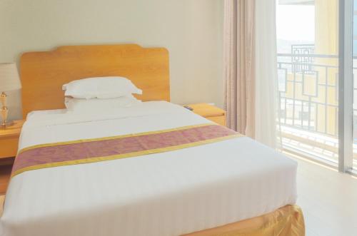 a white bed in a room with a large window at Tropical Plaza Apartments in Kigali