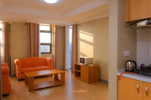 een woonkamer met een bank, een stoel en een tafel bij Tropical Plaza Apartments in Kigali