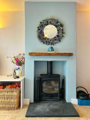 a fireplace with a mirror on top of it at Odun Terrace in Appledore