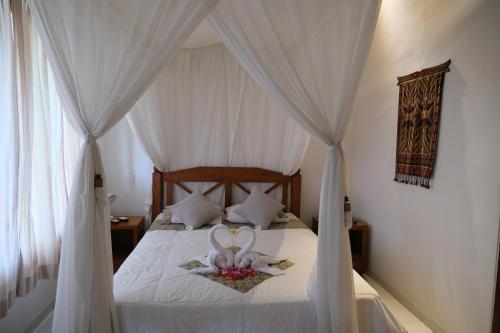 1 dormitorio con cama con dosel y cortinas blancas en Retreat Villa Toraja Baturinggit, en Kubu