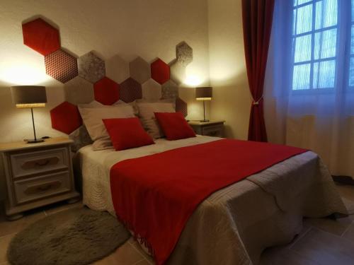 sypialnia z dużym łóżkiem z czerwonymi poduszkami w obiekcie DOMAINE DES 3 CYPRÈS Chambre PIVOINE Chez Nath & Pat w mieście Fumel