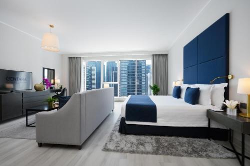 a bedroom with a king sized bed and a couch at Centara West Bay Hotel & Residences Doha in Doha