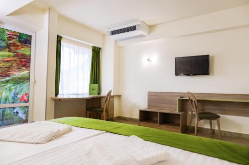 una camera con letto, scrivania e TV di Hotel Olanesti & Spa Medical a Băile Olăneşti