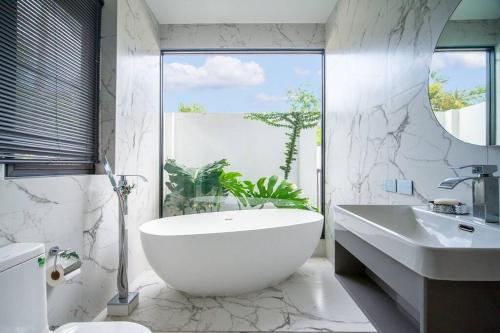 ein Badezimmer mit einer großen weißen Badewanne und einem Waschbecken in der Unterkunft KOTE Private Pool Villa in Nathon Bay