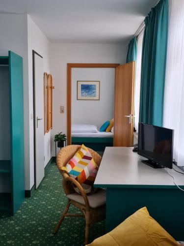une chambre d'hôtel avec un bureau et une chambre dans l'établissement Hotel am Friedberger See, à Friedberg