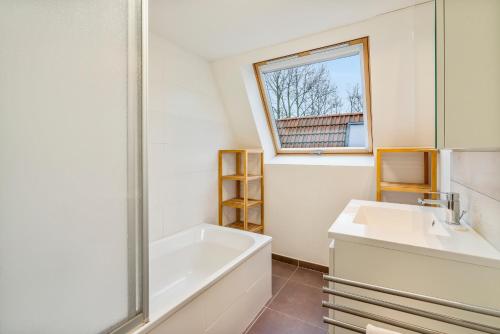 a bathroom with a tub and a sink and a mirror at Casa Kids in De Panne