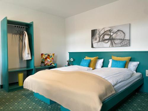 a bedroom with a large bed with blue and yellow pillows at Hotel am Friedberger See in Friedberg