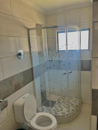 La salle de bains est pourvue d'une douche, de toilettes et d'une fenêtre. dans l'établissement THABAKGOLO GUEST HOUSE, à Ga-Manapane