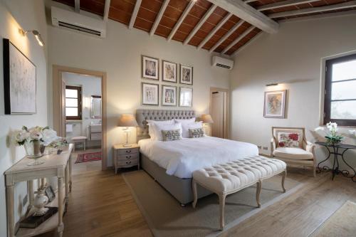 a bedroom with a large white bed and a chair at Borgo Argiano in Castelnuovo Berardenga