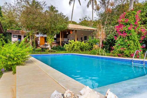 uma piscina em frente a uma casa com flores em Pousada Mar à Vista em Trancoso