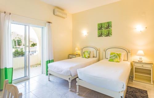 two beds in a room with a window at Hotel Apartamento A Floresta do Jose in Almancil