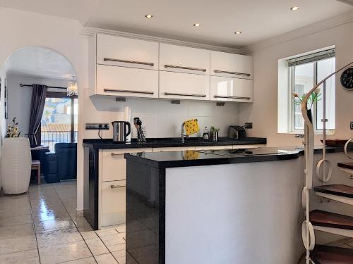 マニルバにある2257-Stunning penthouse first line port sea viewのキッチン(白いキャビネット、黒いカウンタートップ付)