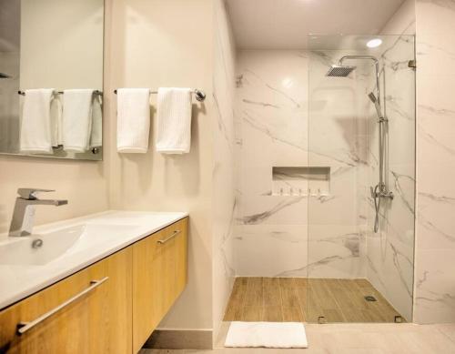 ein weißes Bad mit einer Dusche und einem Waschbecken in der Unterkunft Amazing Apartment with Rooftop Jacuzzi at Bayahibe - Vibe Residences 3BDR in Bayahibe
