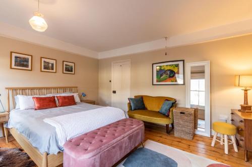 a bedroom with a large bed and a chair at Lindley Terrace - Norfolk Holiday Properties in Norwich
