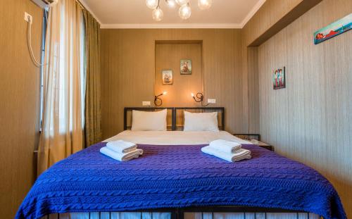 a bedroom with a blue bed with towels on it at Hotel at Gomi 19 in Tbilisi City