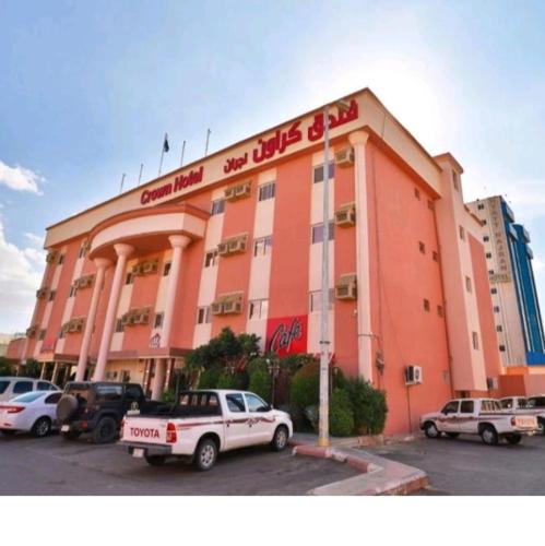 un grand bâtiment orange avec des voitures garées dans un parking dans l'établissement فندق كراون نجران, à Najran