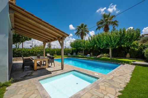 a swimming pool in a yard with a table at Villa Muse in Pitsidia