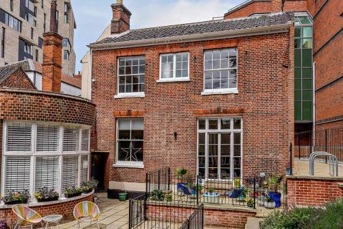 a brick house with chairs and tables in front of it at Host & Stay - All Saints Green Cottage in Norwich
