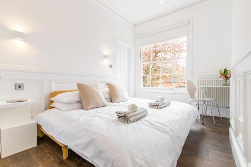 a white bedroom with a large white bed with towels on it at All Saints Green Cottage - Norfolk Holiday Properties in Norwich
