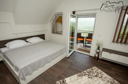 ein Schlafzimmer mit einem großen weißen Bett und einem Balkon in der Unterkunft Villa Ostrovica in Bihać